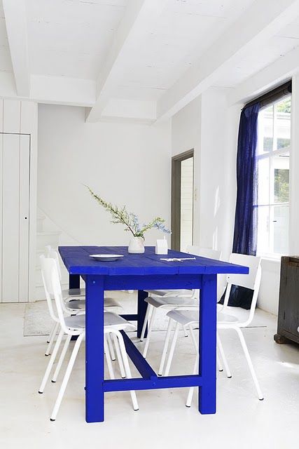 Comedor blanco con mesa y cortinas en azul klein