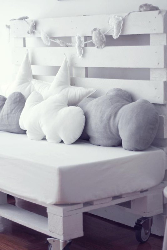 Detalle cama dormitorio infantil con cojines en blanco y gris