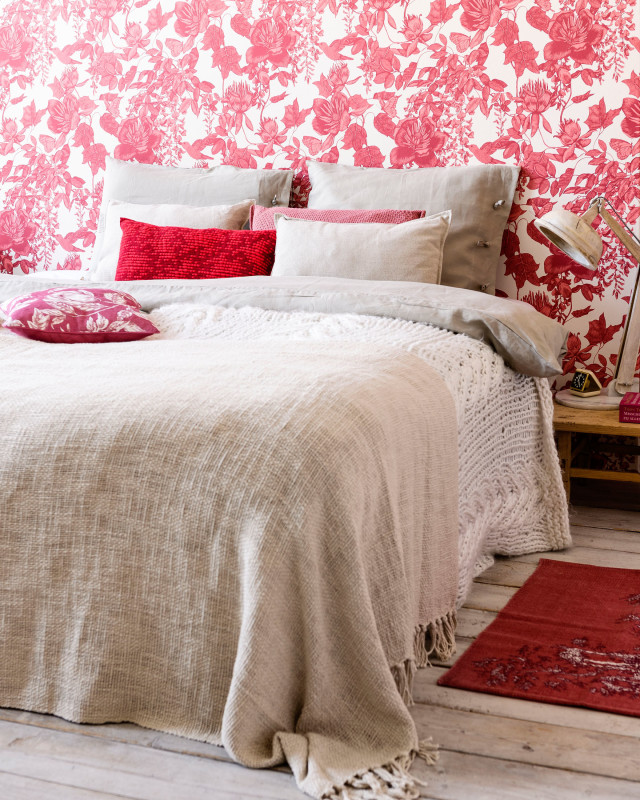 Dormitorio en tonos neutros con papel pintado y cojines en rojo
