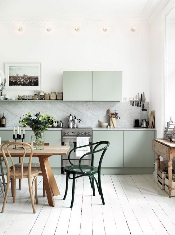 Cocina revestida en marmol, madera pintada blanca y muebles verde pastel