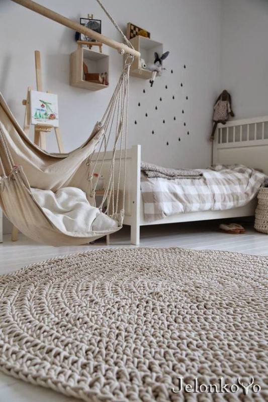 Dormitorio infantiles con tonos neutros con alfombra redonda de ganchillo