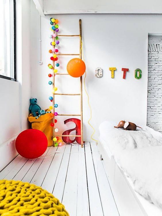 Guinaldas y luces en forma de globo que complementan la divertida decoración de este espacio infantil
