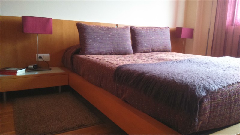 Imagen del cabezal, cama y mesita del dormitorio principal