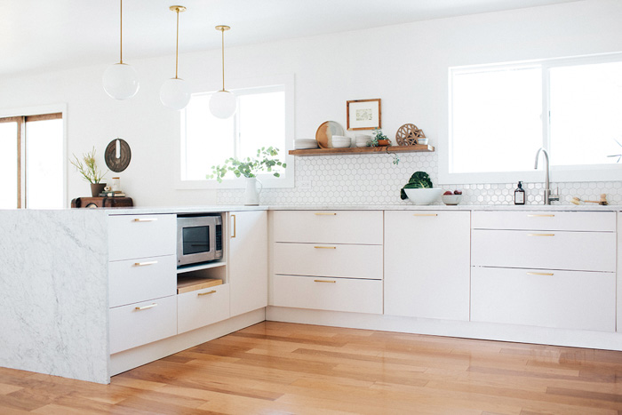 Vista de la cocina reformada con muebles blancos y tiradores dorados