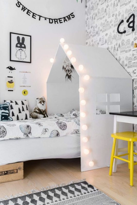 Guirnalda de luces que complementa el cabecero en foma de casa de este dormitorio infantil de estilo nórdico